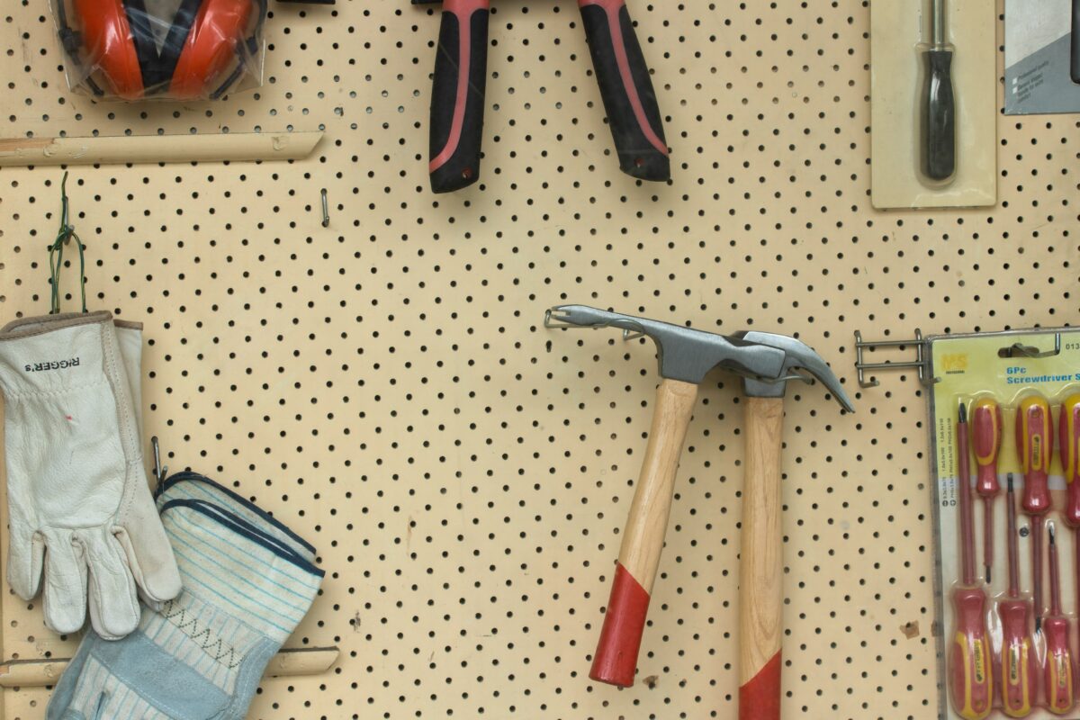 Two wooden-handled brick hammers hang on a brown wall.