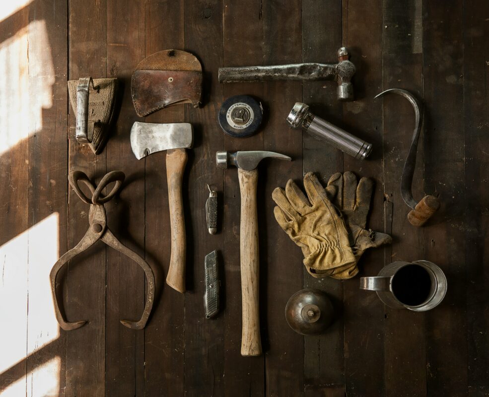 Wood handle brick hammer on a brown table with other various tools