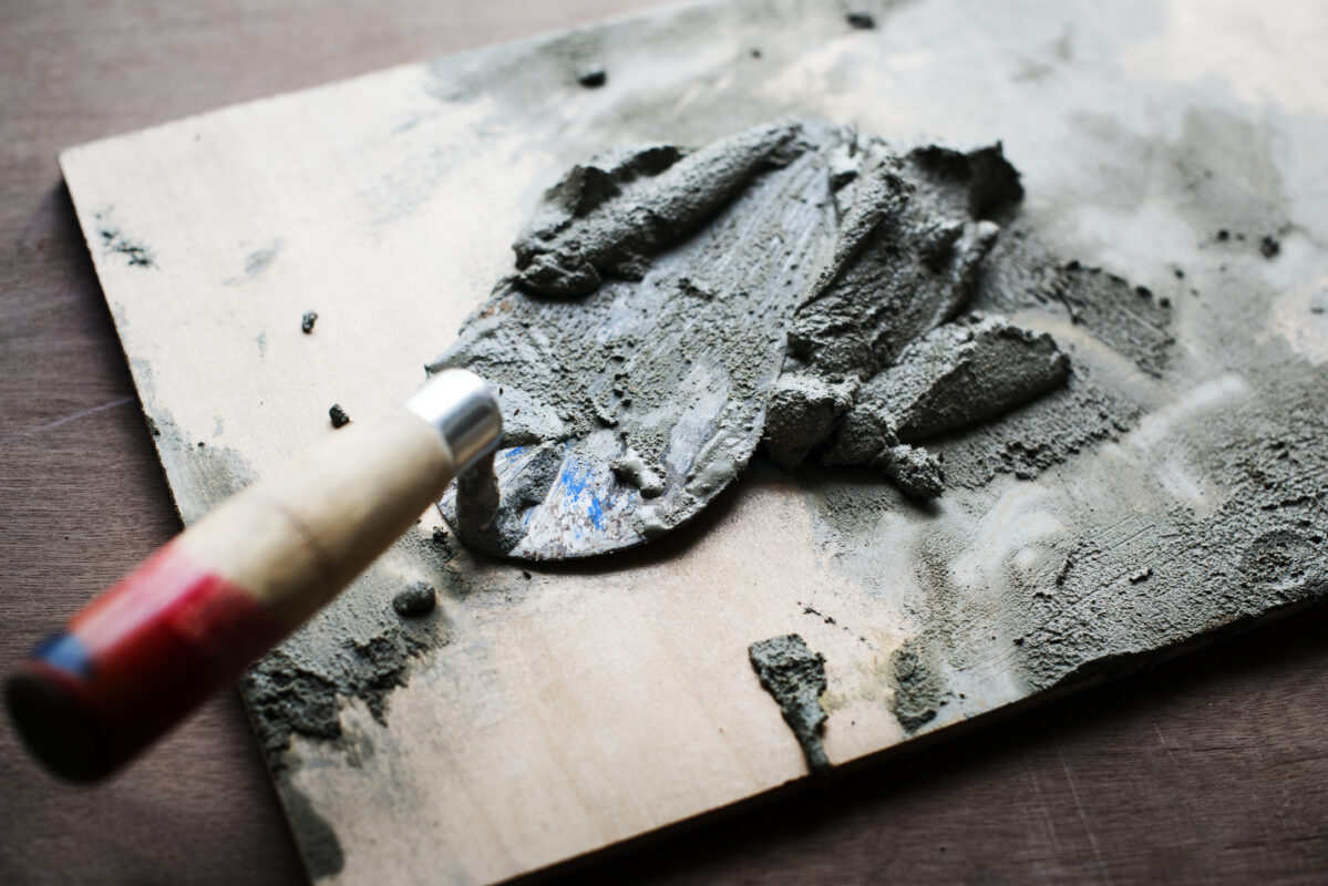 Brick trowel with cement on wood surface