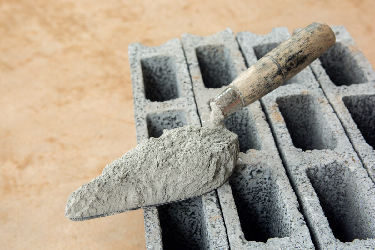 Close up of a brick trowel with cement powder on concrete bricks