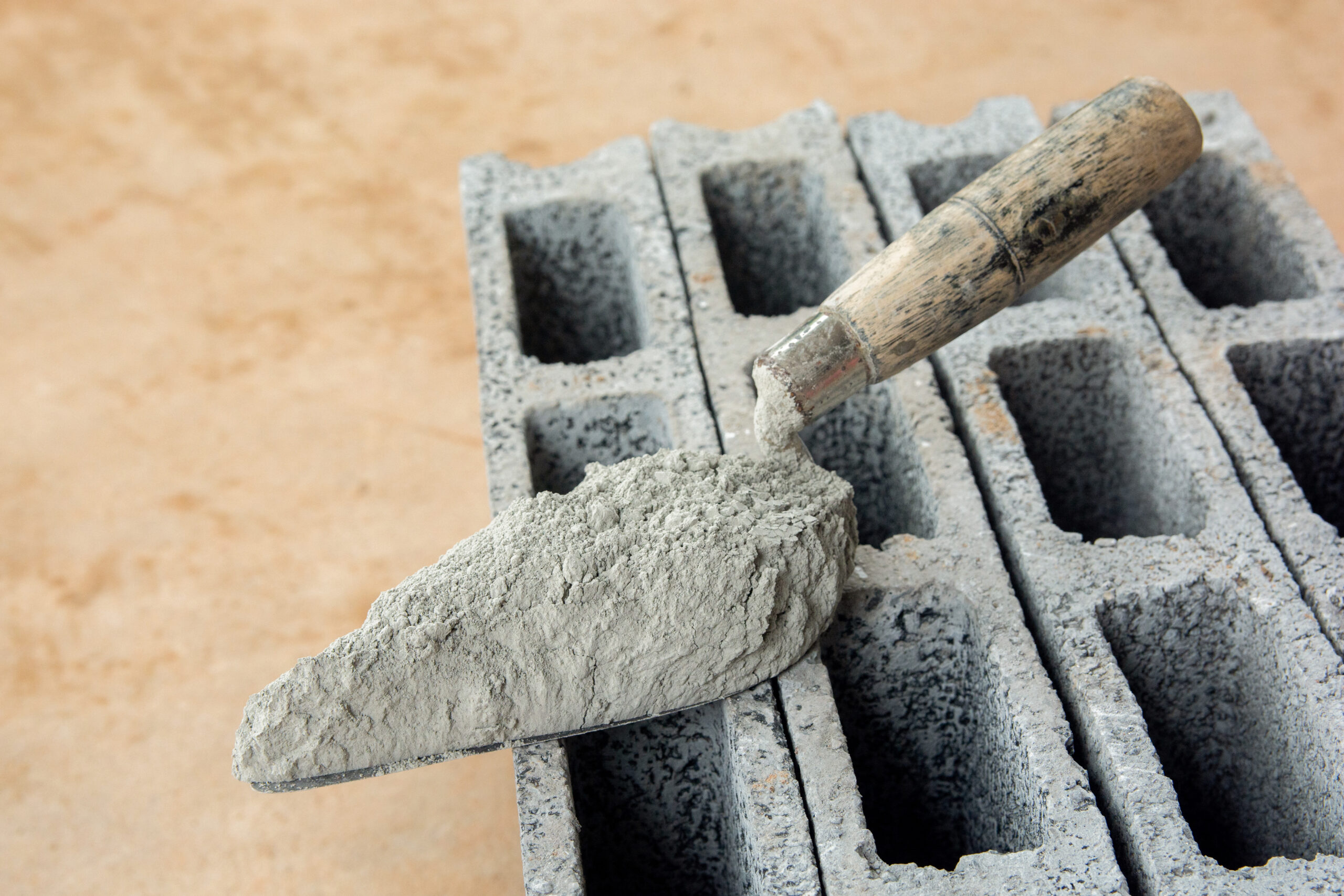 Close up of a brick trowel with cement powder on concrete bricks