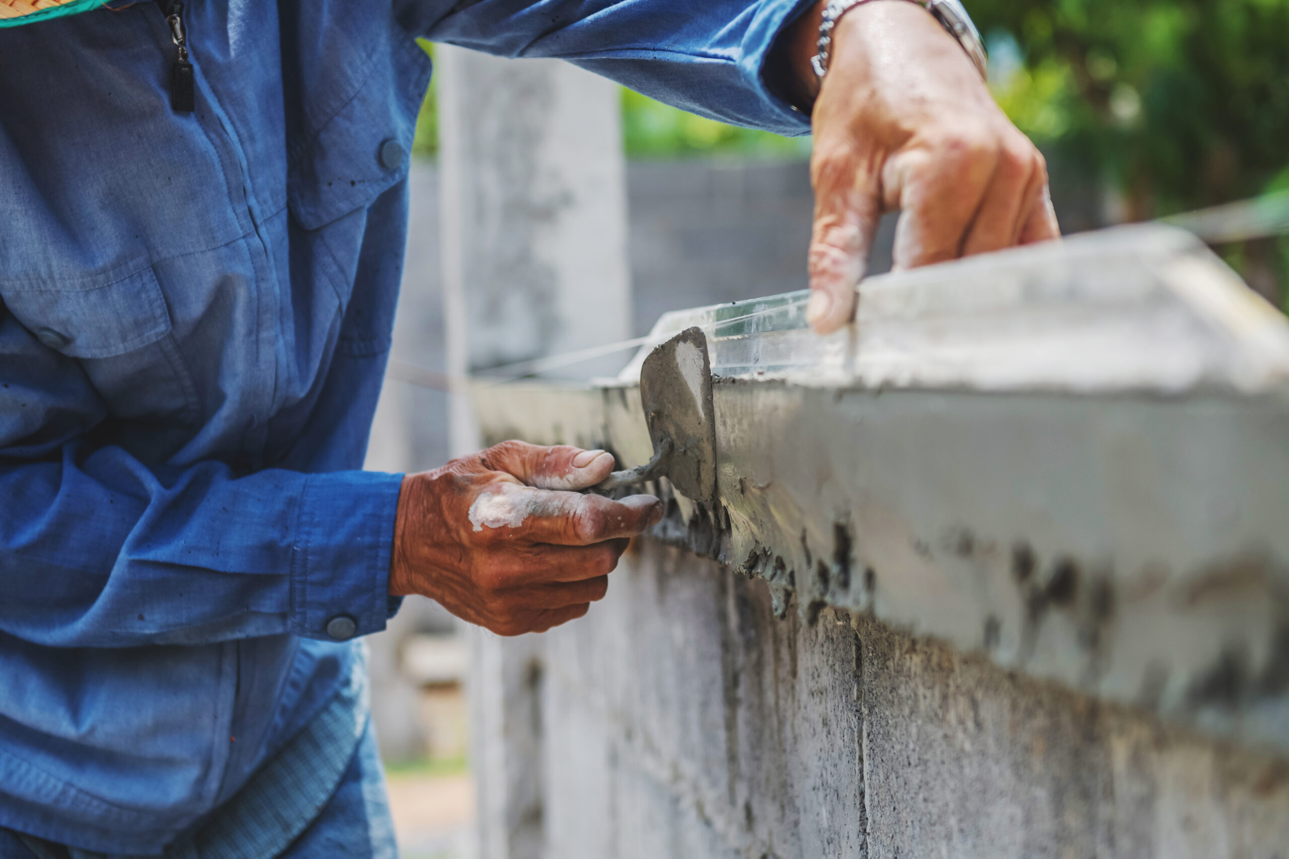 Close-up of a worker plastering a wall with a brick trowel