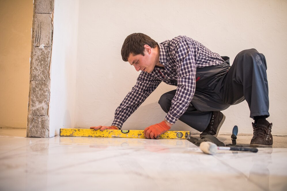 Man measuring the corner of a floor in a room to undertake a flooring project